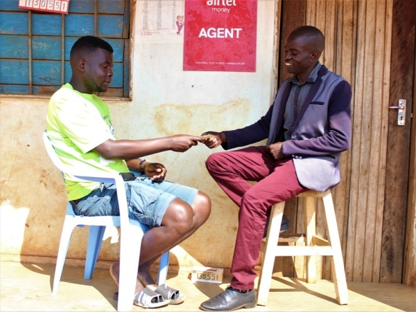 Frank Mataka serving a customer at his airtel money kiosk